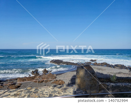 Rocky Ocean Shoreline Under Clear Blue Sky Rocky Ocean Shoreline Under Clear Blue Sky 140782994