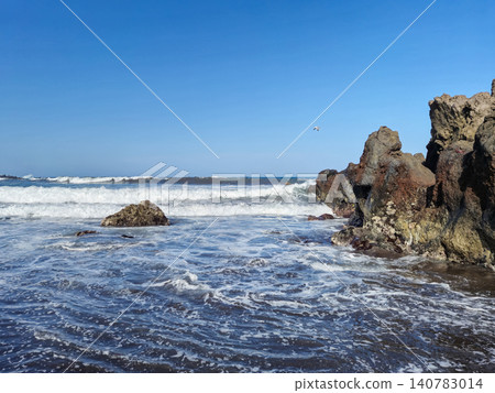 Rocky shoreline with ocean waves and blue sky 140783014