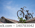 Vintage bicycle perched on a rooftop against a clear blue sky 140783042