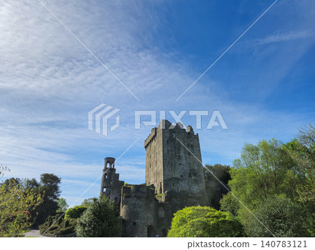 Ruined stone castle tower above green trees and blue sky Ruined stone castle tower above green trees and blue sky 140783121