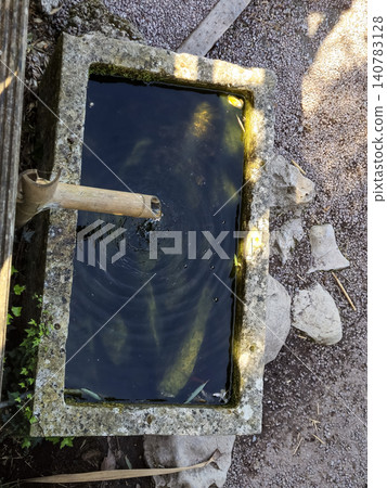 Stone water tank with bamboo spout outdoors Stone water tank with bamboo spout outdoors 140783128