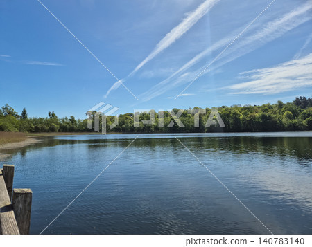 Tranquil lake landscape with blue sky and forest Tranquil lake landscape with blue sky and forest 140783140