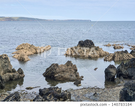 Rocky coastline with calm sea and distant headland Rocky coastline with calm sea and distant headland 140783184