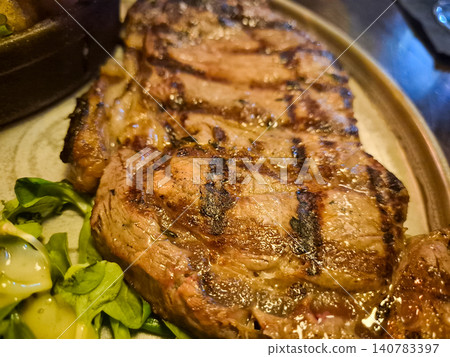 Grilled steak on a plate with greens Grilled steak on a plate with greens 140783397