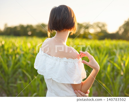 Woman in white dress walking through sunset field in Croatia Woman in white dress walking through sunset field in Croatia 140783502