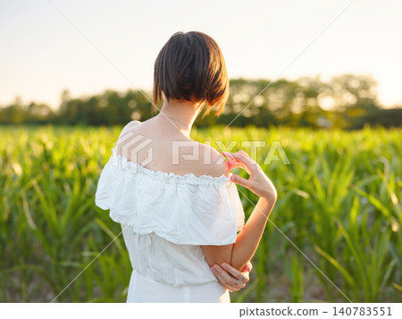 Woman in white dress walking through sunset field in Croatia Woman in white dress walking through sunset field in Croatia 140783551