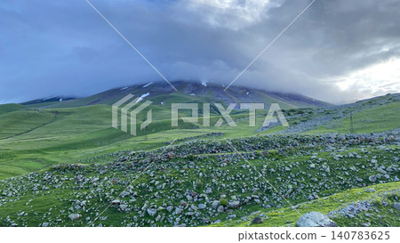 Panoramic view near Didi Abuli in Georgia with green mountain meadows, scattered snow patches and dramatic sky Panoramic view near Didi Abuli in Georgia with green mountain meadows, scattered snow patches and dramatic sky 140783625