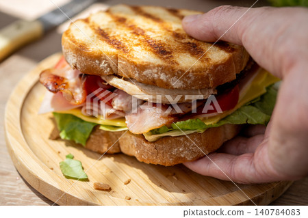 Hand Picking Up Fresh Grilled Club Sandwich Hand Picking Up Fresh Grilled Club Sandwich 140784083