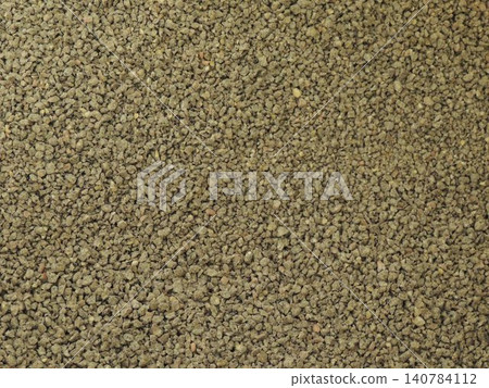 A grainy matte texture of fine, loose granules. The uniform, porous surface consists of randomly distributed particles in shades of brown, olive, and beige. Textured pebble background. A grainy matte texture of fine, loose granules. The uniform, porous surface consists of randomly distributed particles in shades of brown, olive, and beige. Textured pebble background. 140784112