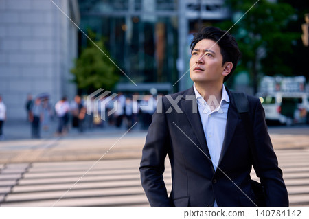 一位三十多歲的日本上班族,身穿西裝,抬頭望著城市景觀。 一位三十多歲的日本上班族,身穿西裝,抬頭望著城市景觀。 140784142