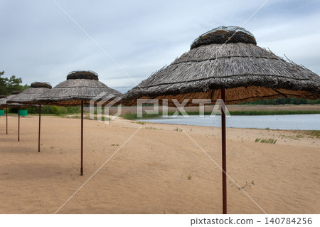 Straw umbrellas on the beach and a cloudy sky Straw umbrellas on the beach and a cloudy sky 140784256