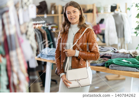 Young woman choosing handbag in clothing store Young woman choosing handbag in clothing store 140784262