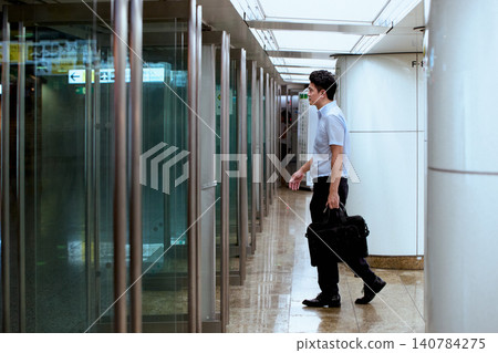 一位三十多歲的日本商人手提包，走過地下通道，可能是通勤或旅行途中。 140784275