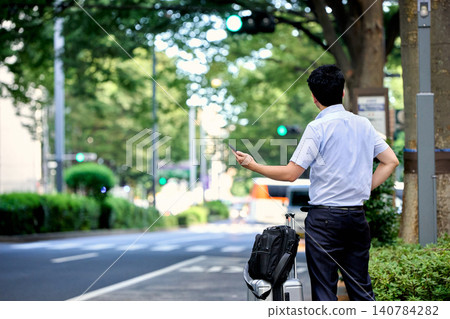 一位日本商人,臉部被遮擋,背部也看不到,他正在使用智慧型手機應用程式叫計程車。 一位日本商人,臉部被遮擋,背部也看不到,他正在使用智慧型手機應用程式叫計程車。 140784282