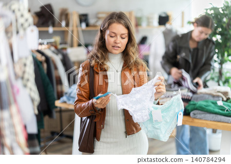 Female shopper selects panties in fashionable clothing boutique. Female shopper selects panties in fashionable clothing boutique. 140784294