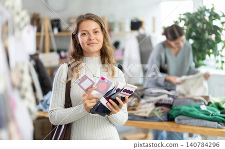 Attentive young girl client choosing new socks in clothing market Attentive young girl client choosing new socks in clothing market 140784296