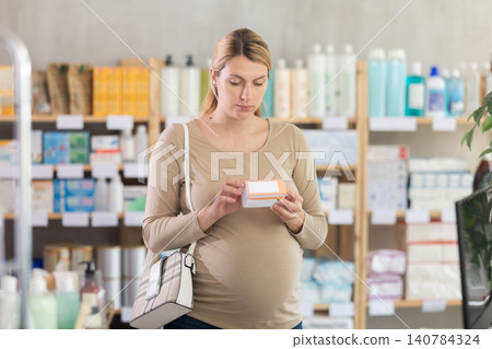 Pregnant woman choose pills of supplements in pharmacy Pregnant woman choose pills of supplements in pharmacy 140784324