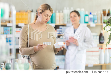 Pregnant woman choosing pills with help of pharmacist Pregnant woman choosing pills with help of pharmacist 140784364