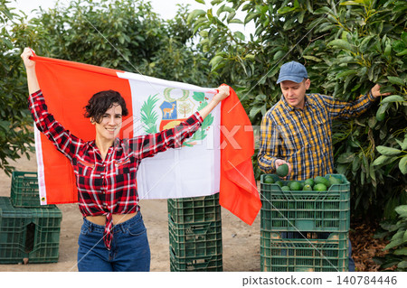 Smiling farmers holding Peru flag in avocado plantation Smiling farmers holding Peru flag in avocado plantation 140784446