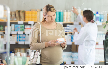 Pregnant woman choosing vitamins or supplements in pharmacy Pregnant woman choosing vitamins or supplements in pharmacy 140784460