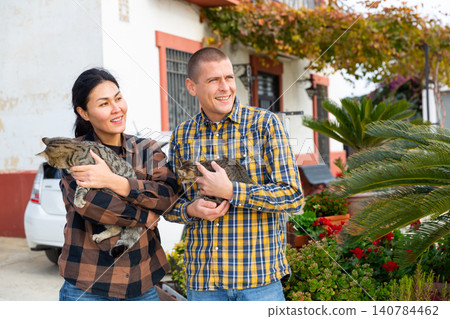 Couple with kitties standing outdoors Couple with kitties standing outdoors 140784462