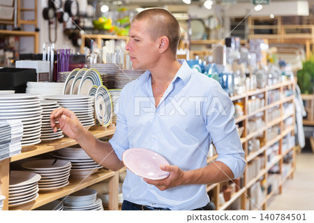 Ordinary male buyer chooses plates in store closeup Ordinary male buyer chooses plates in store closeup 140784501