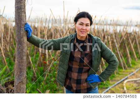 Portrait of positive female farmer on background of pea plantation on farm field 140784503