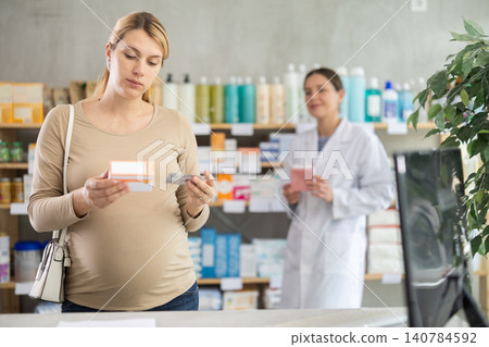 Pharmacist assisting expecting woman choosing medication at drugstore Pharmacist assisting expecting woman choosing medication at drugstore 140784592