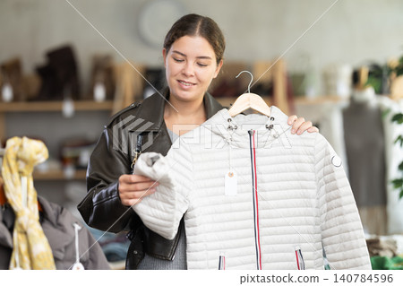 Young woman choosing down jacket in clothing store 140784596