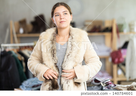 Glad young girl trying on fur coat in clothing store Glad young girl trying on fur coat in clothing store 140784601
