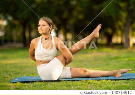 Girl enjoying outdoor yoga practice in green summer park Girl enjoying outdoor yoga practice in green summer park 140784613