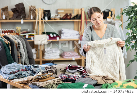 Young woman chooses sweater in clothing store Young woman chooses sweater in clothing store 140784632