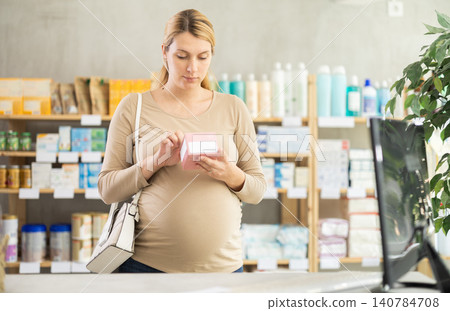 Pregnant woman customer choosing pills in box in drugstore Pregnant woman customer choosing pills in box in drugstore 140784708