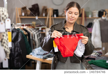 Young woman chooses panties in clothing store Young woman chooses panties in clothing store 140784746