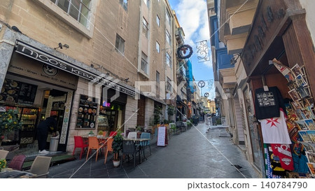 A narrow, sloping street lined with restaurants and souvenir shops photographed during the Christmas season A narrow, sloping street lined with restaurants and souvenir shops photographed during the Christmas season 140784790