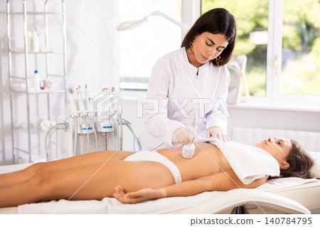Female doctor making belly beauty procedure with ice hummer Female doctor making belly beauty procedure with ice hummer 140784795