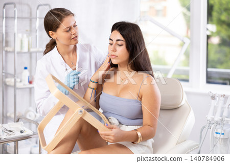 Aesthetician giving professional advice before facial skin treatments to young brunette Aesthetician giving professional advice before facial skin treatments to young brunette 140784906