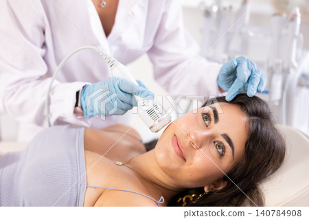 Brunette girl having facial beauty procedure with ice hummer Brunette girl having facial beauty procedure with ice hummer 140784908