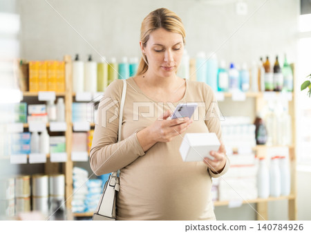Pregnant woman scanning qr code of pills Pregnant woman scanning qr code of pills 140784926