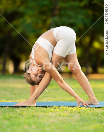 Young girl performing Pyramid Pose in green summer park Young girl performing Pyramid Pose in green summer park 140784980