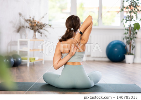 Experienced girl fitness club teacher performs lotus asana, padmasana 140785013