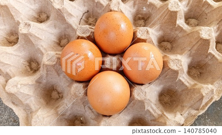 Close-up of four fresh uncooked eggs in a tray or egg carton. 140785040