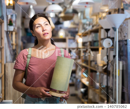 Woman choosing table lamp in store Woman choosing table lamp in store 140785062