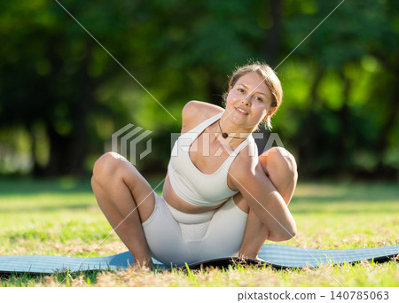 Girl enjoying outdoor yoga practice in green summer park 140785063