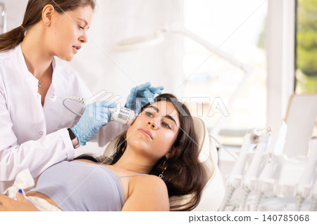 Brunette girl having facial beauty procedure with ice hummer 140785068