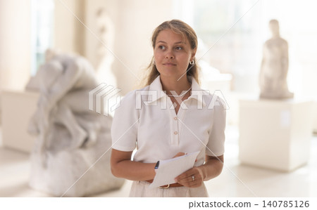 Woman with sheet piece of paper in hands view sculpture in museum hall Woman with sheet piece of paper in hands view sculpture in museum hall 140785126