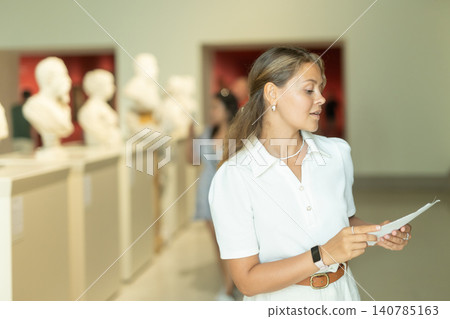 Portrait of attractive woman visiting sculpture hall in historical museum and looking at exhibits Portrait of attractive woman visiting sculpture hall in historical museum and looking at exhibits 140785163