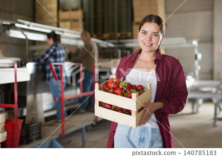 Attractive female gardener holding crate with strawberry at warehouse Attractive female gardener holding crate with strawberry at warehouse 140785183