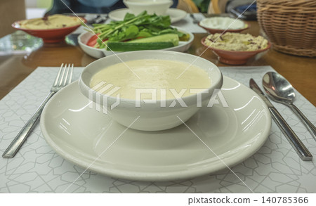 Bowl of fresh homemade cream soup puree with bread and vegetables on wooden table. Creamy garlic soup served at the restaurant. Eating healthy concept. Nobody, selective focus Bowl of fresh homemade cream soup puree with bread and vegetables on wooden table. Creamy garlic soup served at the restaurant. Eating healthy concept. Nobody, selective focus 140785366