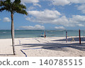 Tropical beach featuring volleyball net and palm tree 140785515